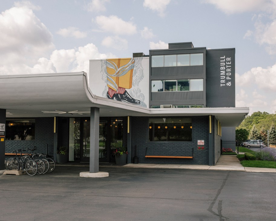 Trumbull & Porter hotel exterior with mid-century modern architecture, mural, and bicycles parked outside in Detroit's Corktown neighborhood.