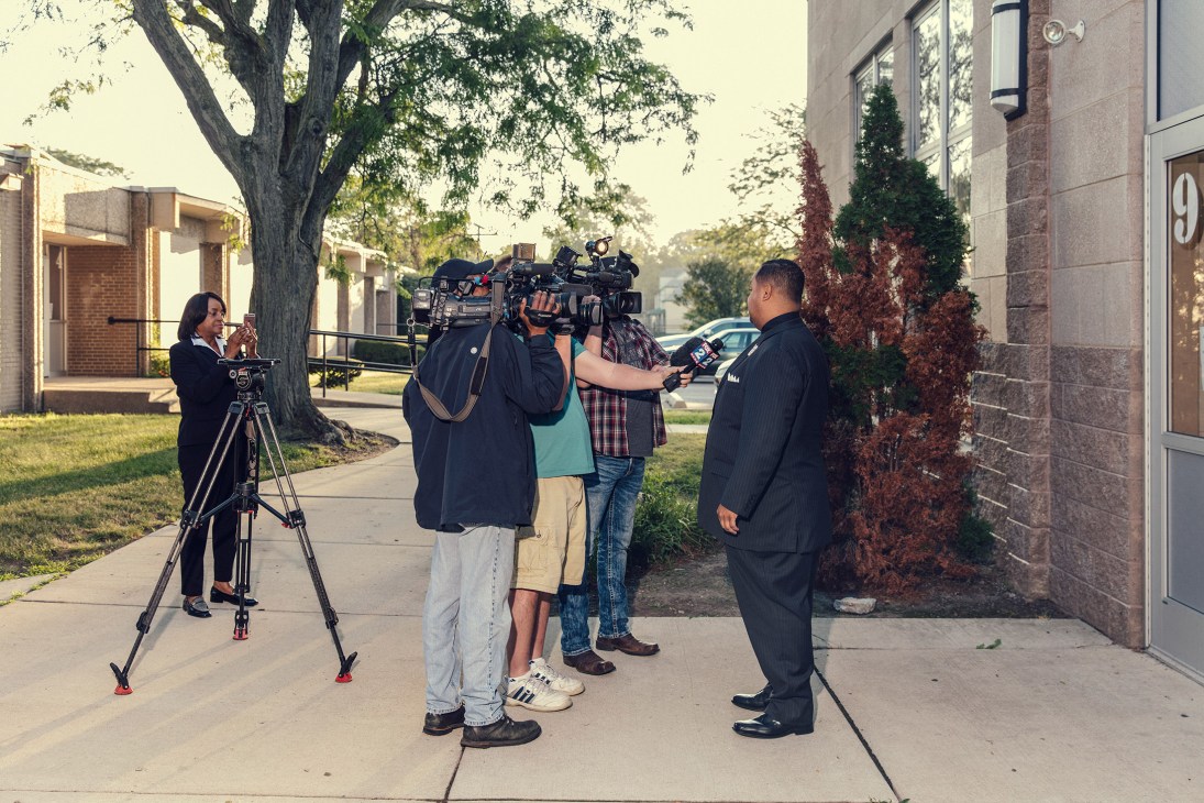 Mayoral candidate Coleman A Young II being interviewed by news crew outside a brick residential building.