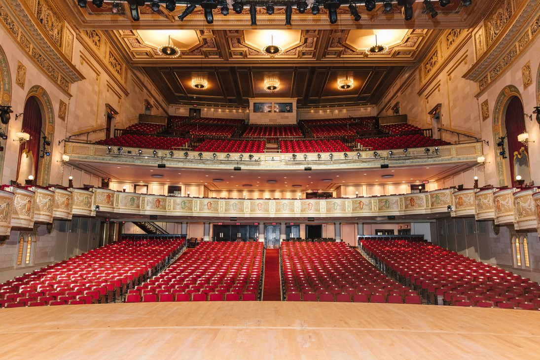 Interior of Detroit Orchestra Hall with ornate gold ceiling, red velvet seats, and multiple balcony levels.