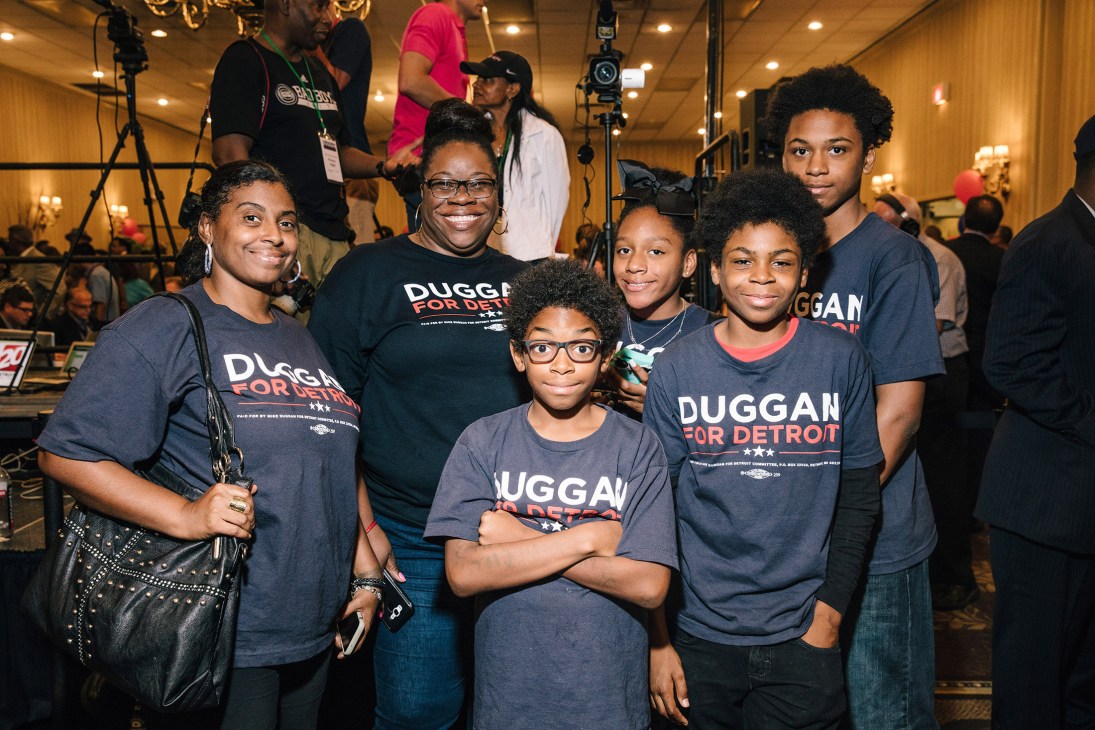A group of supporters wearing Duggan for Detroit campaign t-shirts pose together at a mayoral election event.