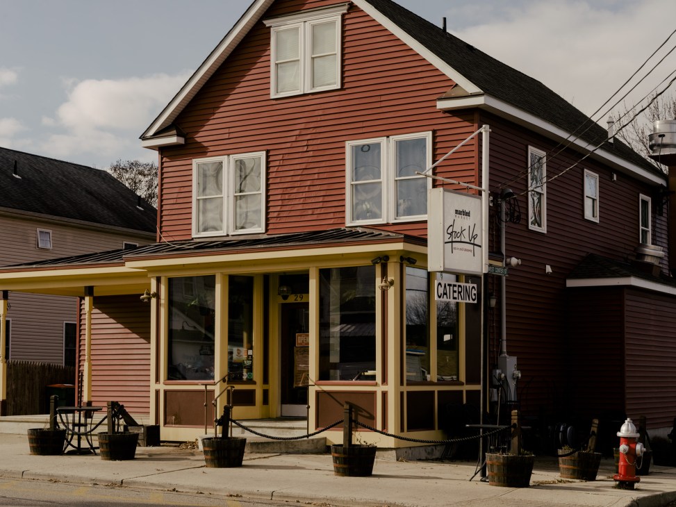 Red-painted storefront of Stock Up deli on Beacon's Main Street with yellow trim and large windows.