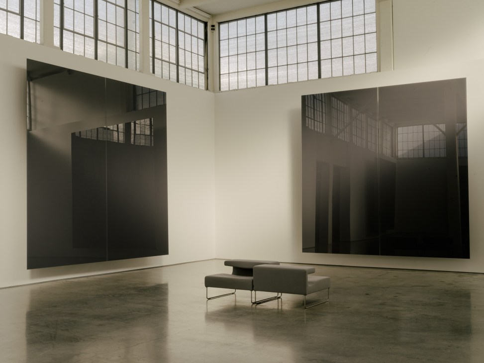 Minimalist art gallery interior with large black abstract panels and skylights