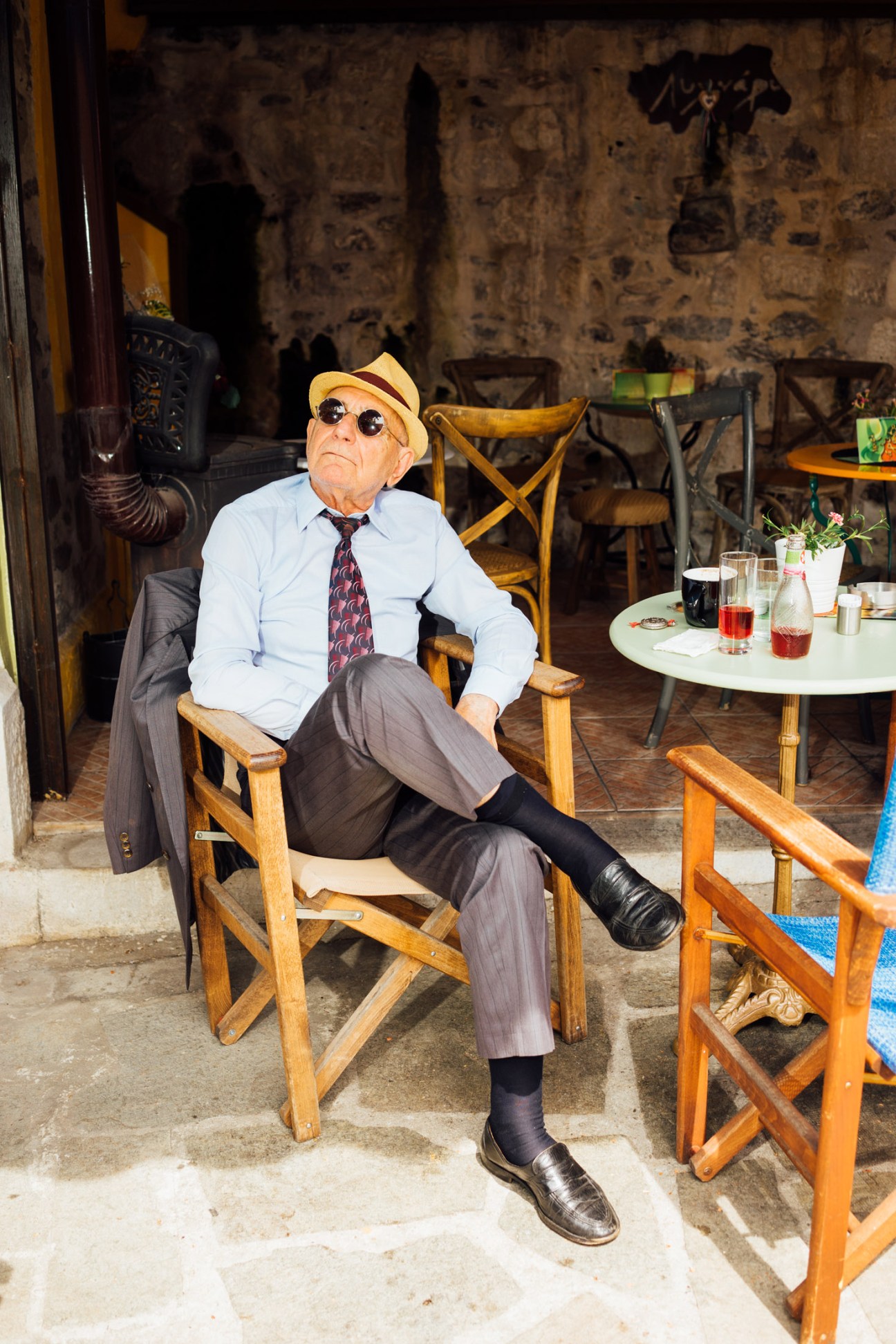 A man in sunglasses and a straw hat sits at Karaoli Square in Kavala, Greece.