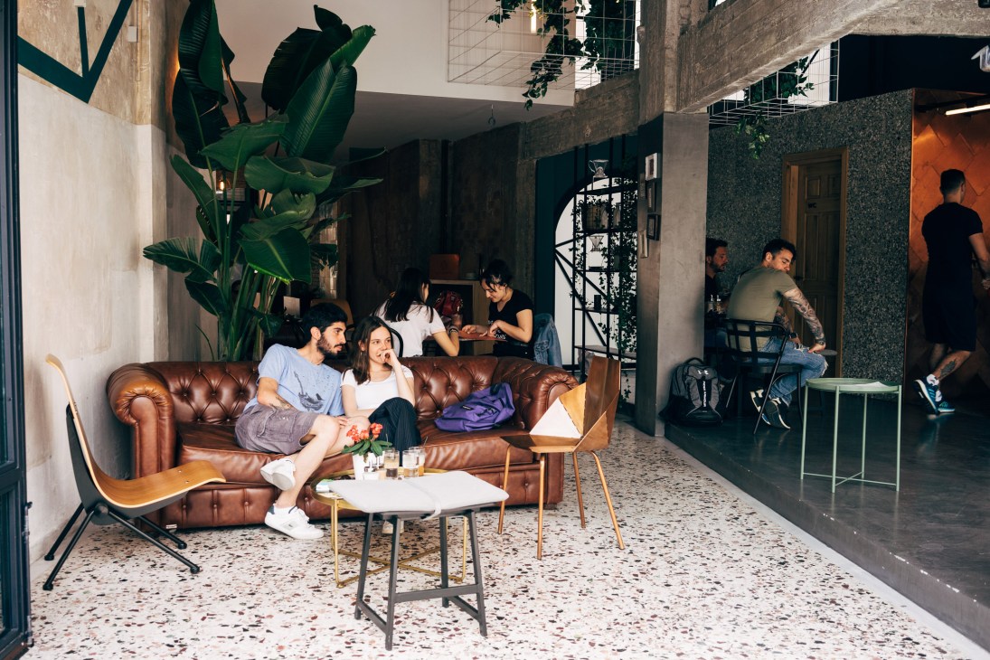 Interior of Black Drop coffee shop with customers seated on brown leather sofa and terrazzo flooring.