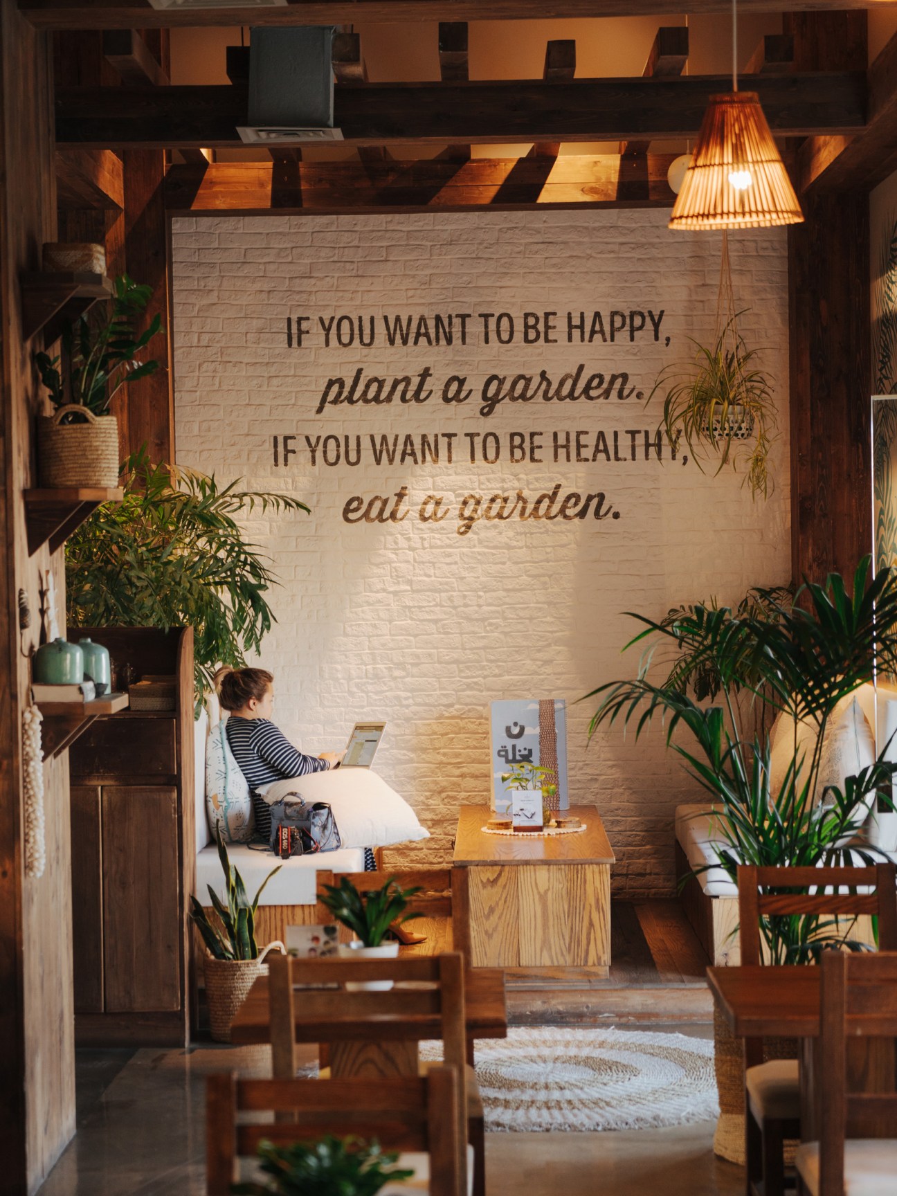 Interior of Evergreen Organics café with wooden furniture, hanging plants, and motivational wall text about gardening and health.