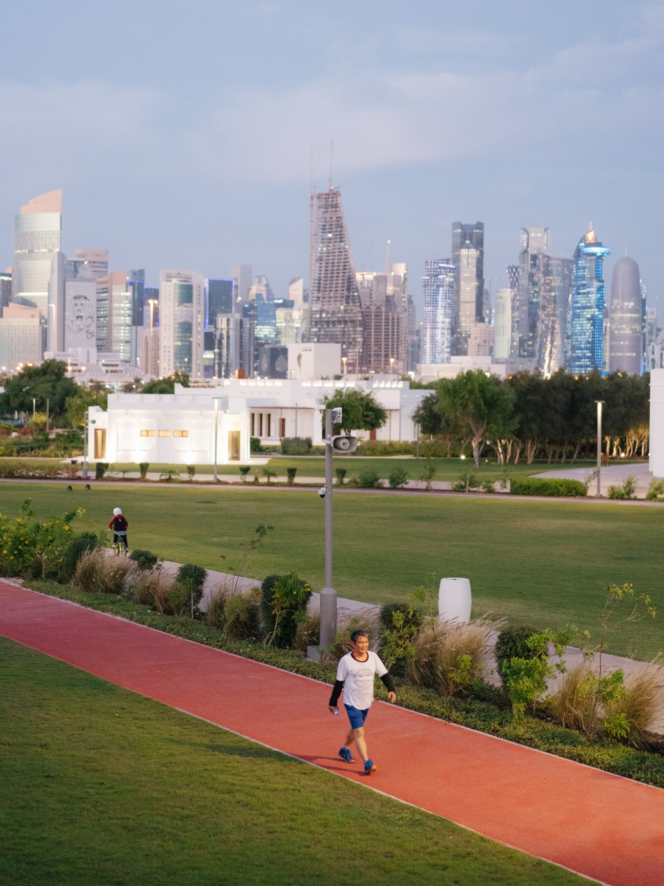 Runner jogging on red track in Al Bidda Park with Chicago skyline in background