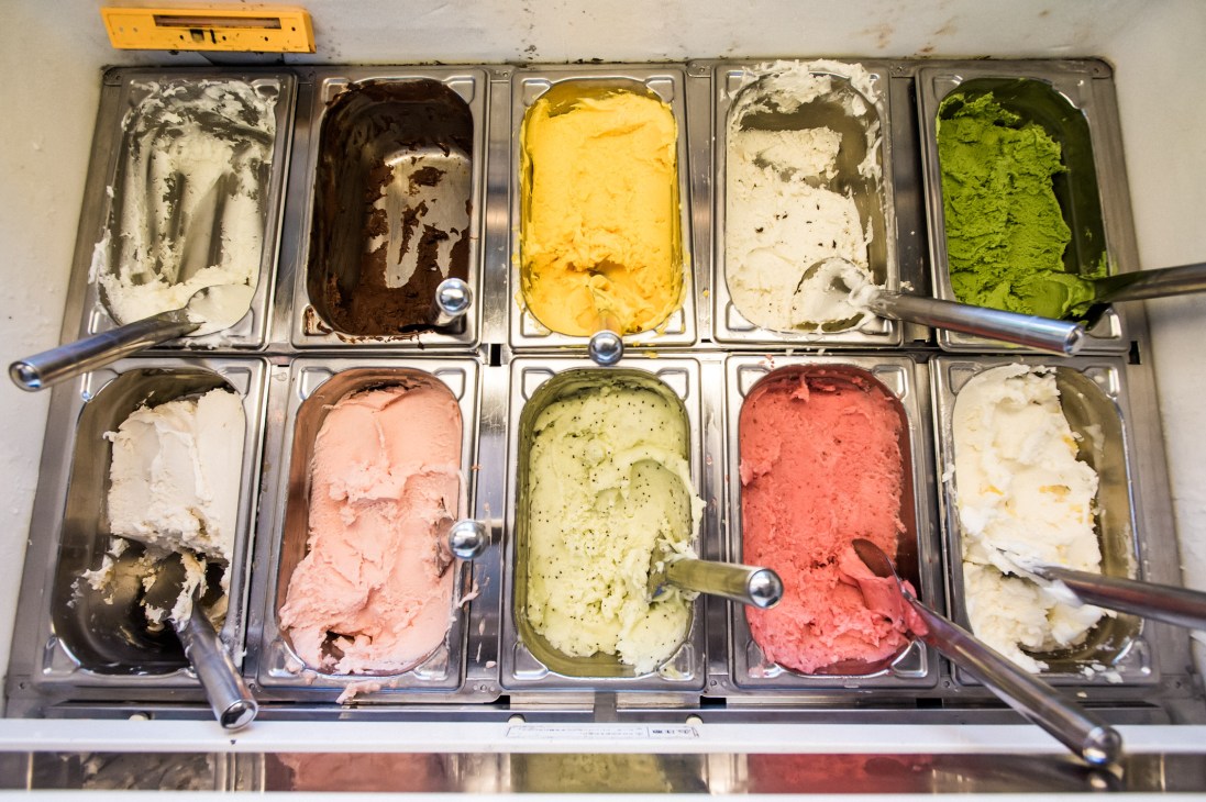 Ice cream display case with ten metal bins containing various colored gelato flavors from white to green to pink