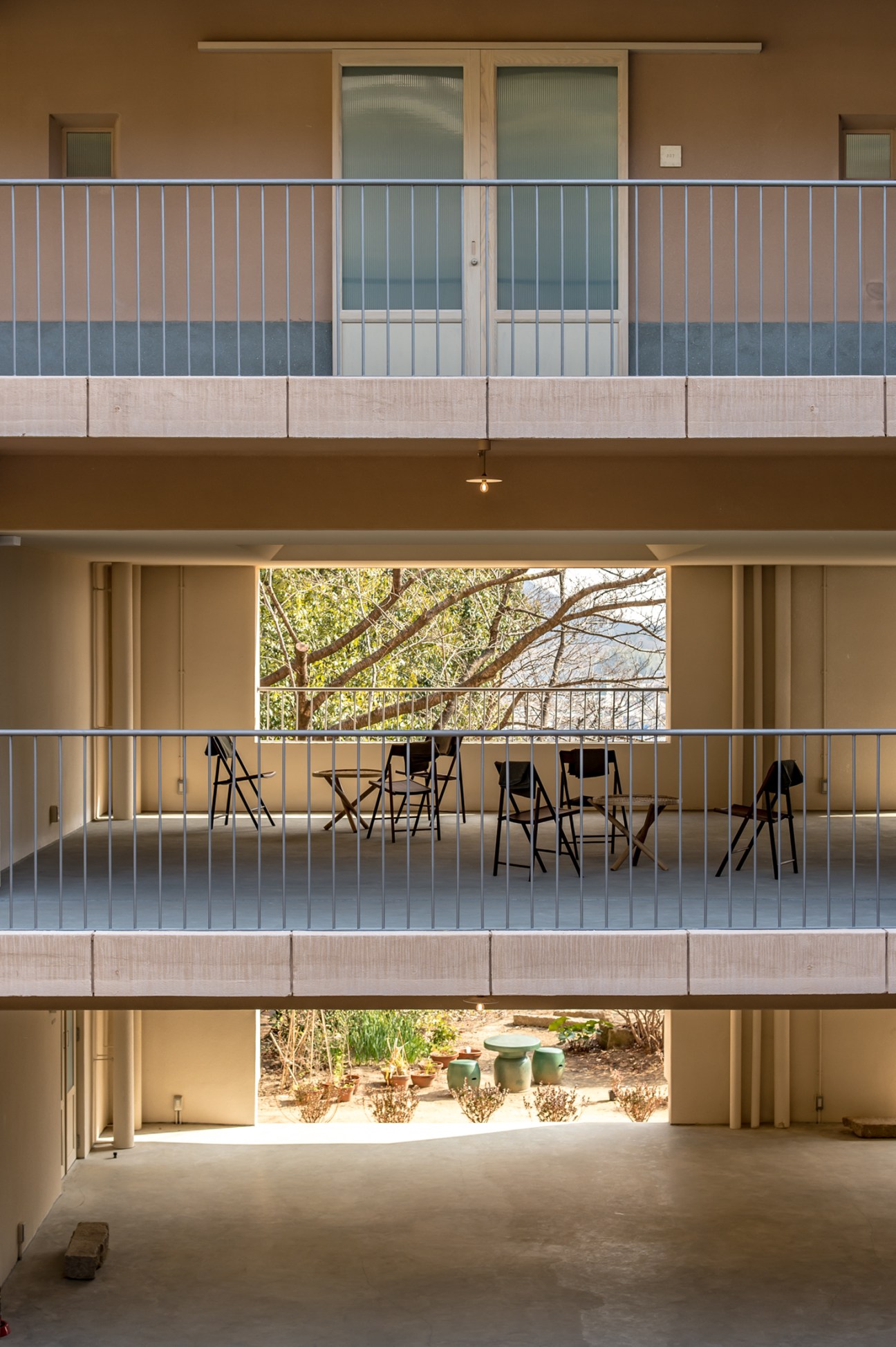 Multi-level outdoor terraces with metal railings, wooden windows, and views of cherry trees and greenery at Lantern Onomichi Garden hotel.