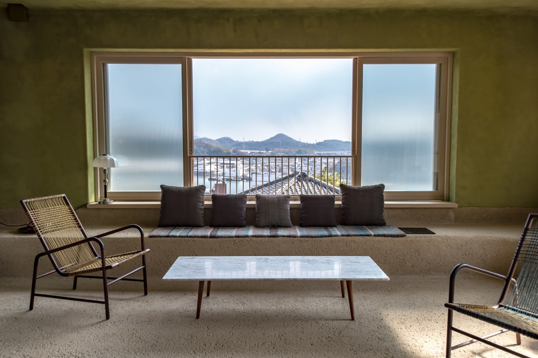 Library with expansive windows overlooking the Setouchi Inland Sea and mountains at Lantern Onomichi Garden hotel.