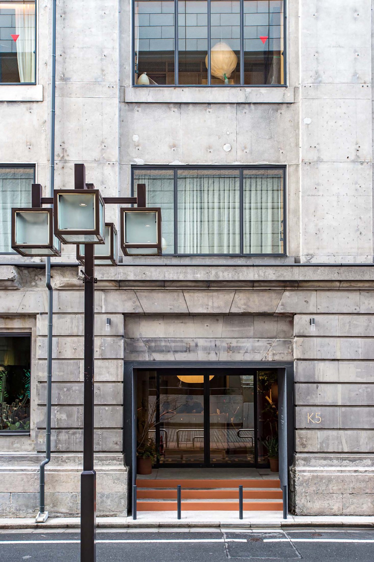 Modern concrete building facade with glass windows, entrance marked K5, and distinctive cube-shaped light fixtures