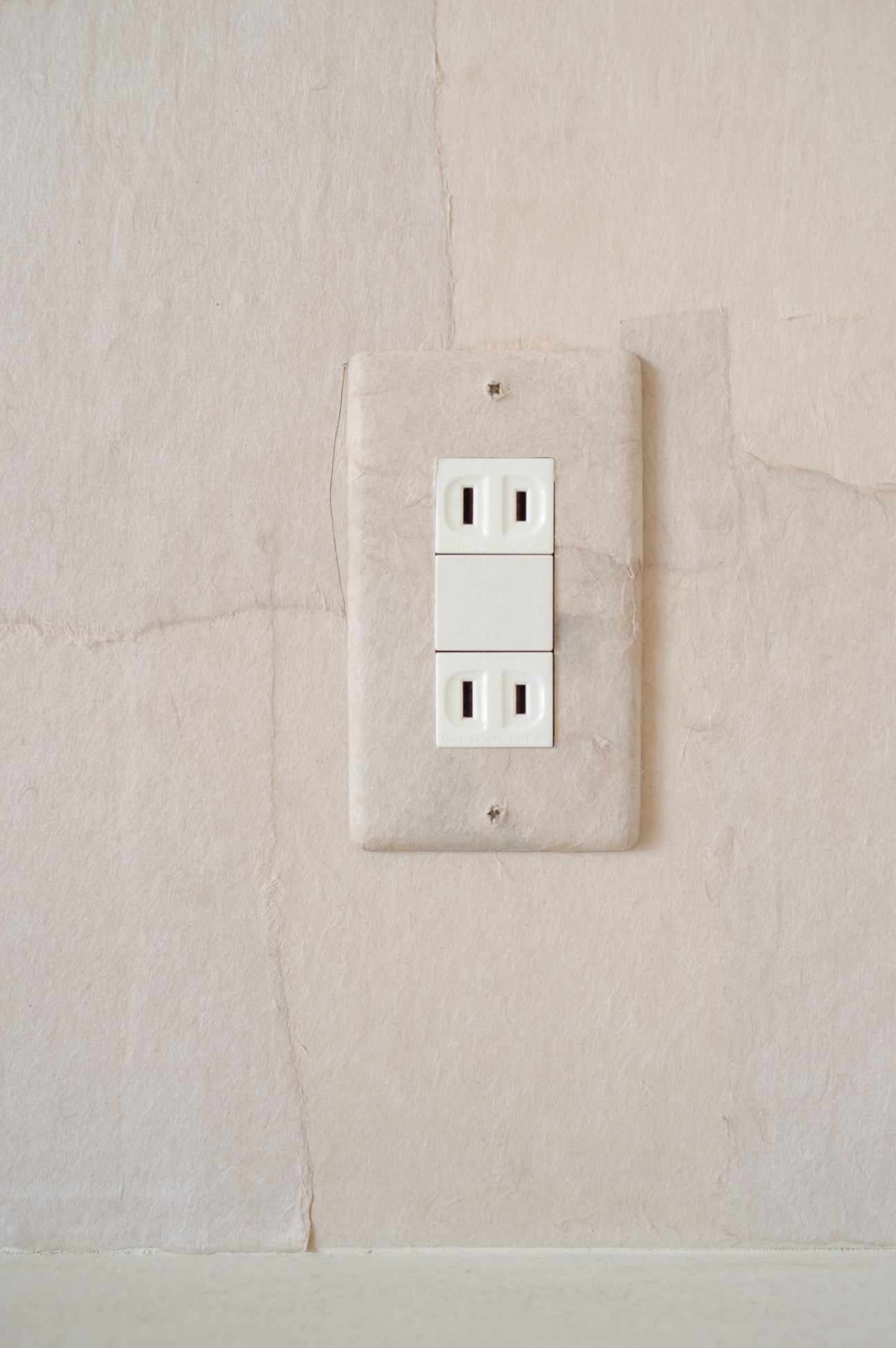 White electrical outlets mounted on a textured cream-colored plaster wall at Lantern Onomichi Garden hotel.