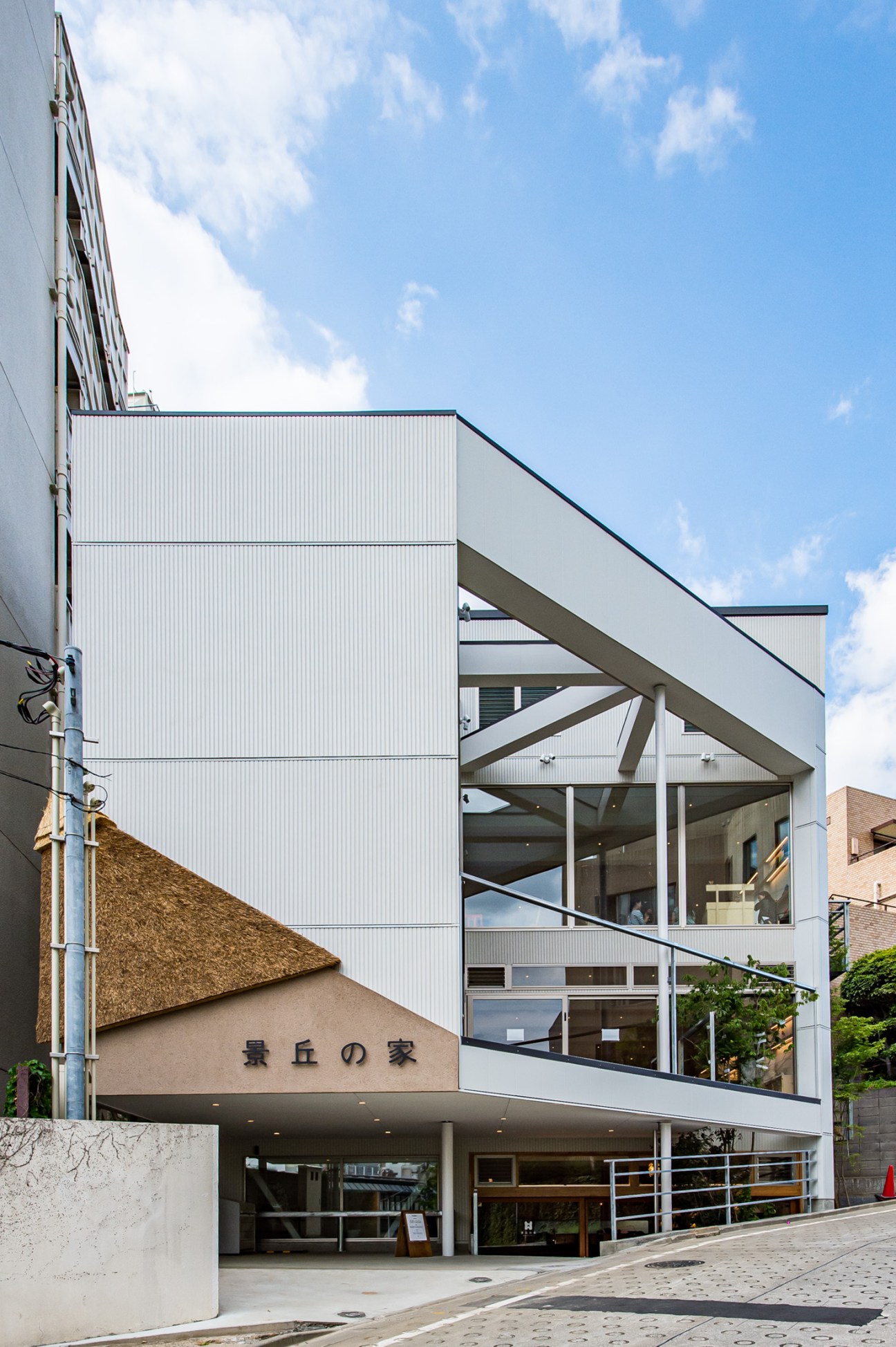 Exterior of Kageoka no Ie, a five-storey Tokyo community centre with white metal cladding and large windows.