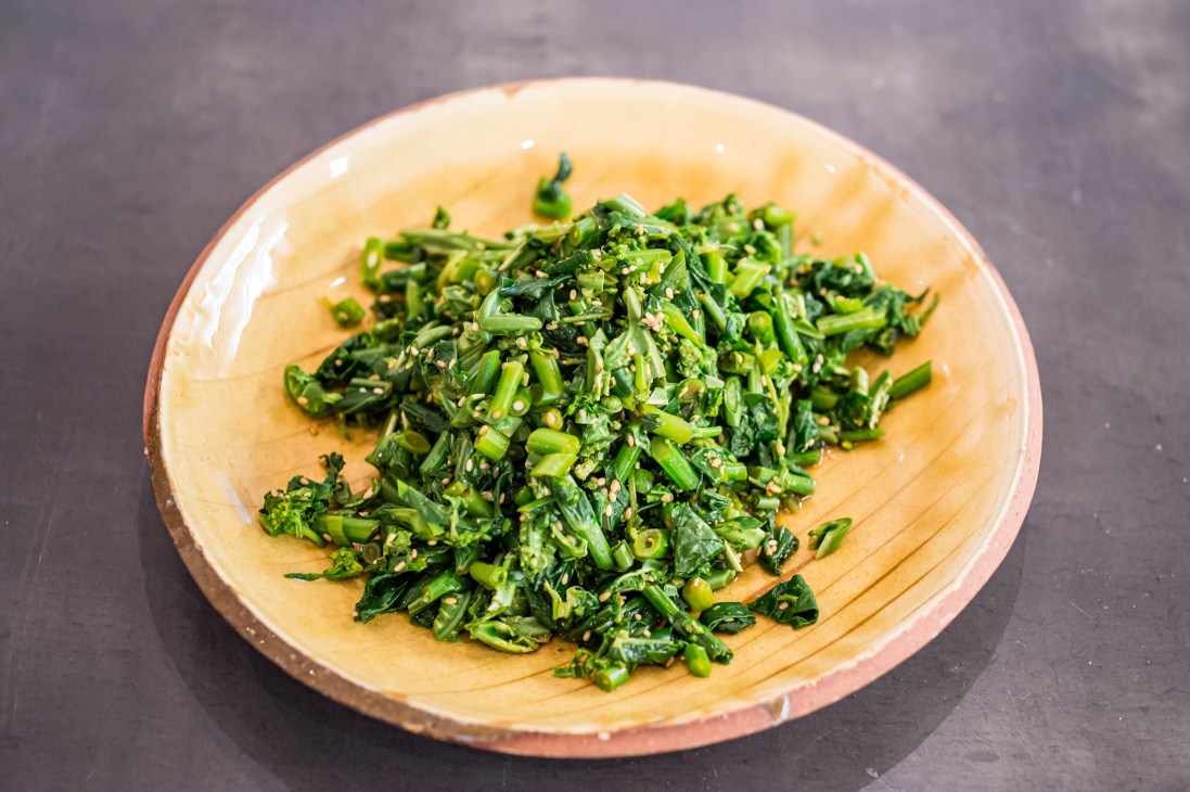 Chopped yomogi leaves and green vegetables on a ceramic plate.