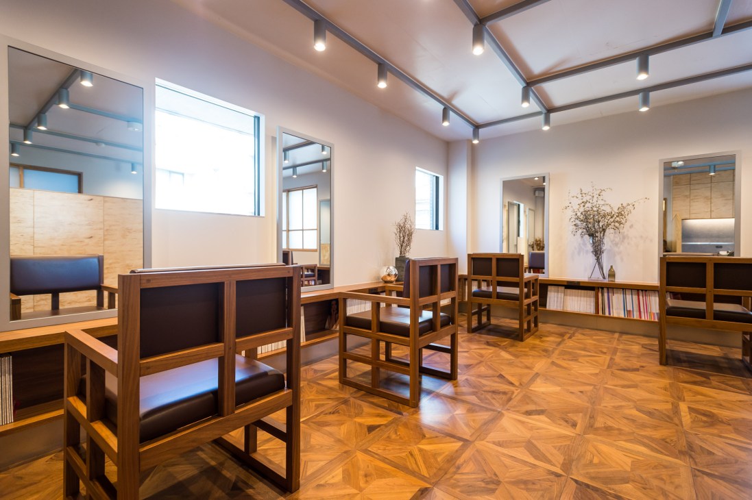 Make-up room in Linda salon featuring wooden furniture, mirrors, and bright skylight ceiling.