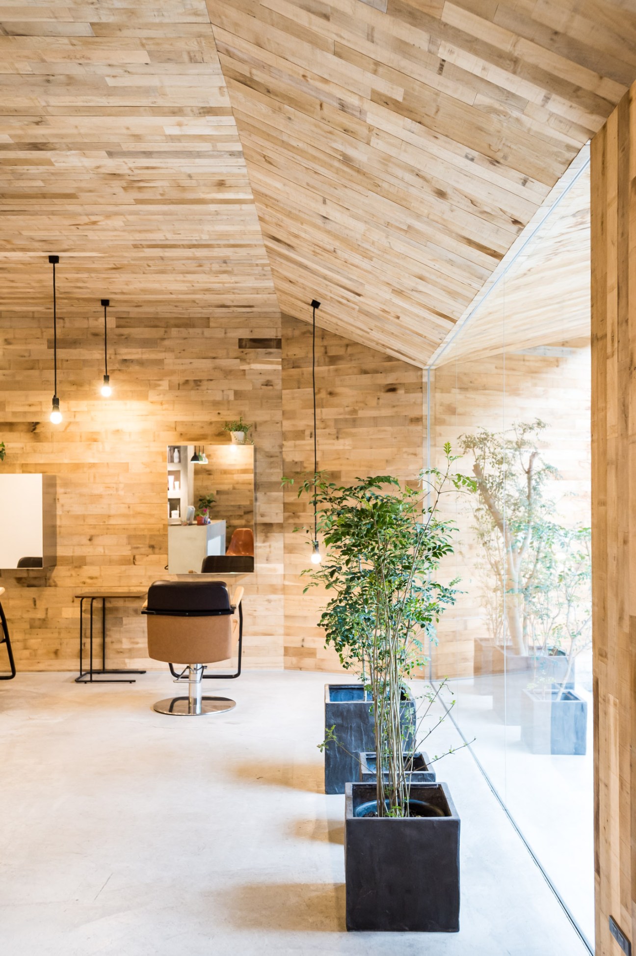 Interior of Mook salon featuring oak-paneled walls and ceiling with pendant lighting and a styling chair.