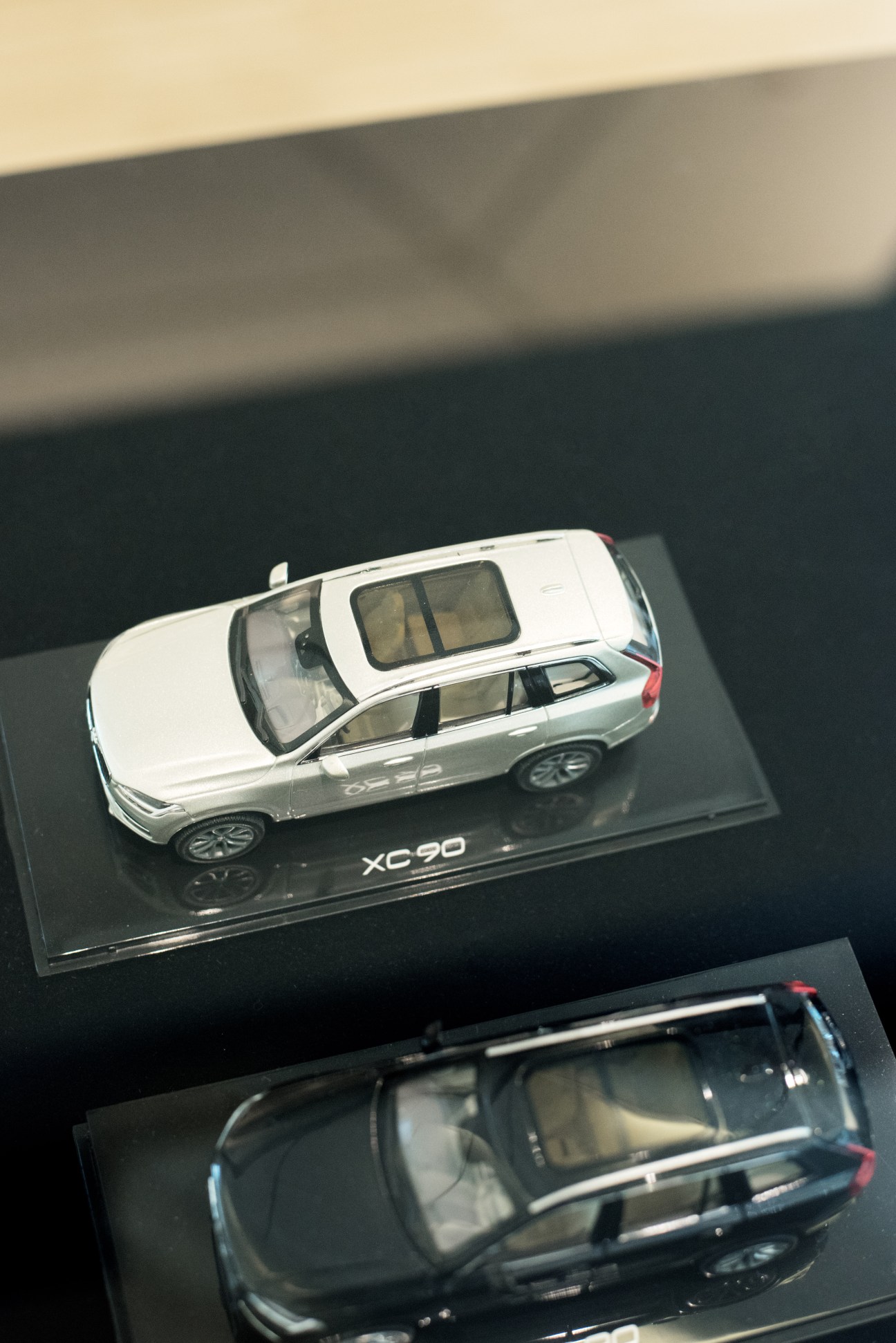 White Volvo XC90 model car displayed in clear case on dark surface