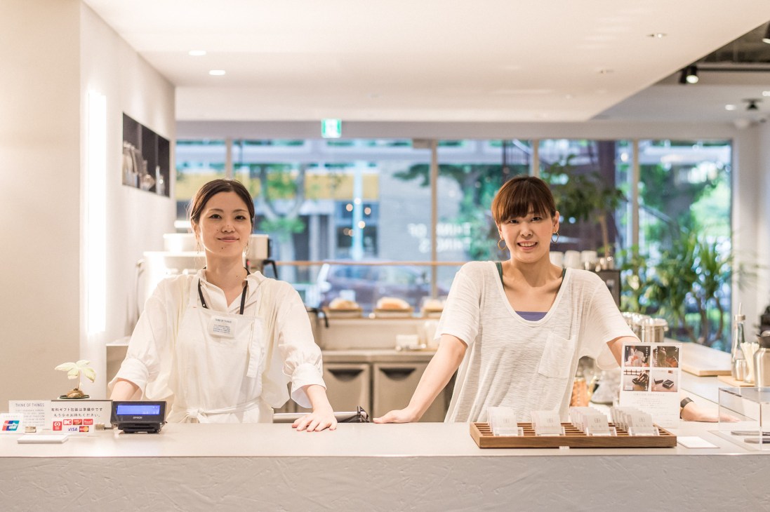 Two female shop staff members standing behind a white counter in a modern retail store