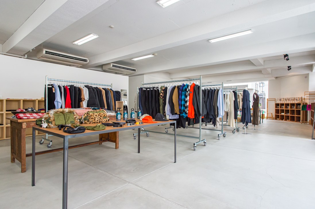 Interior of Ref lifestyle shop in Hiroshima displaying clothing on racks and merchandise on wooden display table.