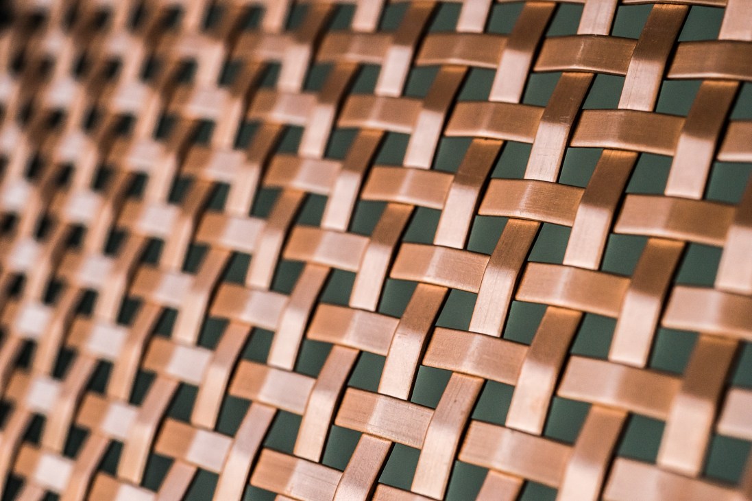 Close-up of interwoven bronze slats in a woven pattern with varying metallic tones.