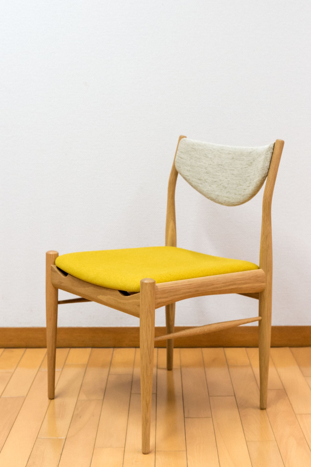 Merino oak dining chair by Keita Watanabe with yellow seat cushion and cream back.