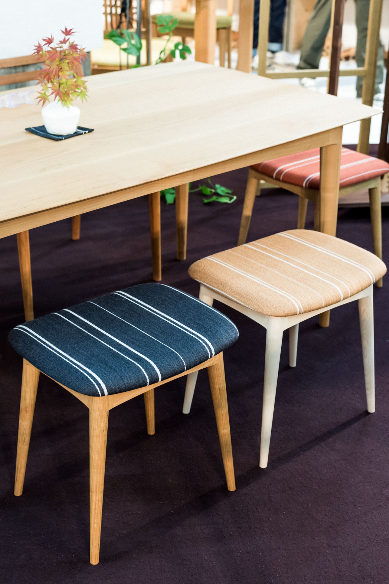 Elfin stools by Hiroyuki Matsufuji of Hitokei displayed around a light wood dining table with potted plants.