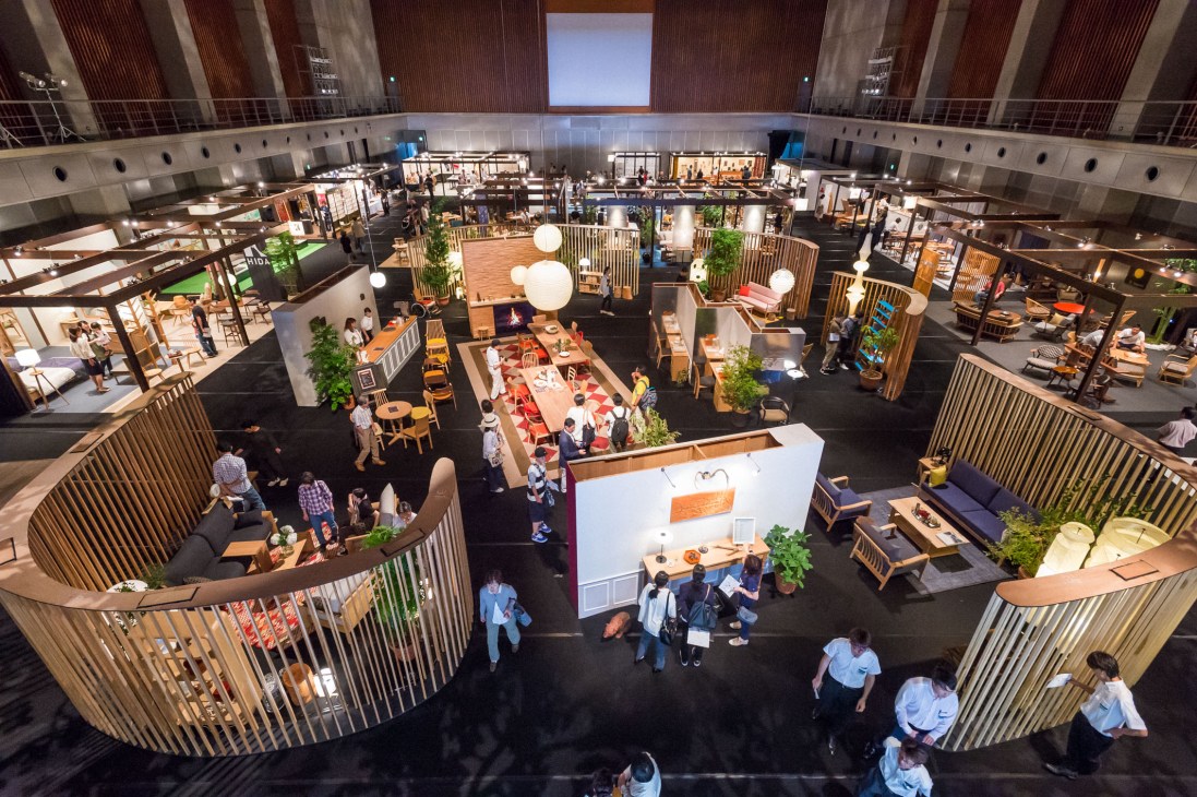 Aerial view of Hida Furniture Festival main venue with wooden display booths, furniture showrooms, and visitors on black flooring.