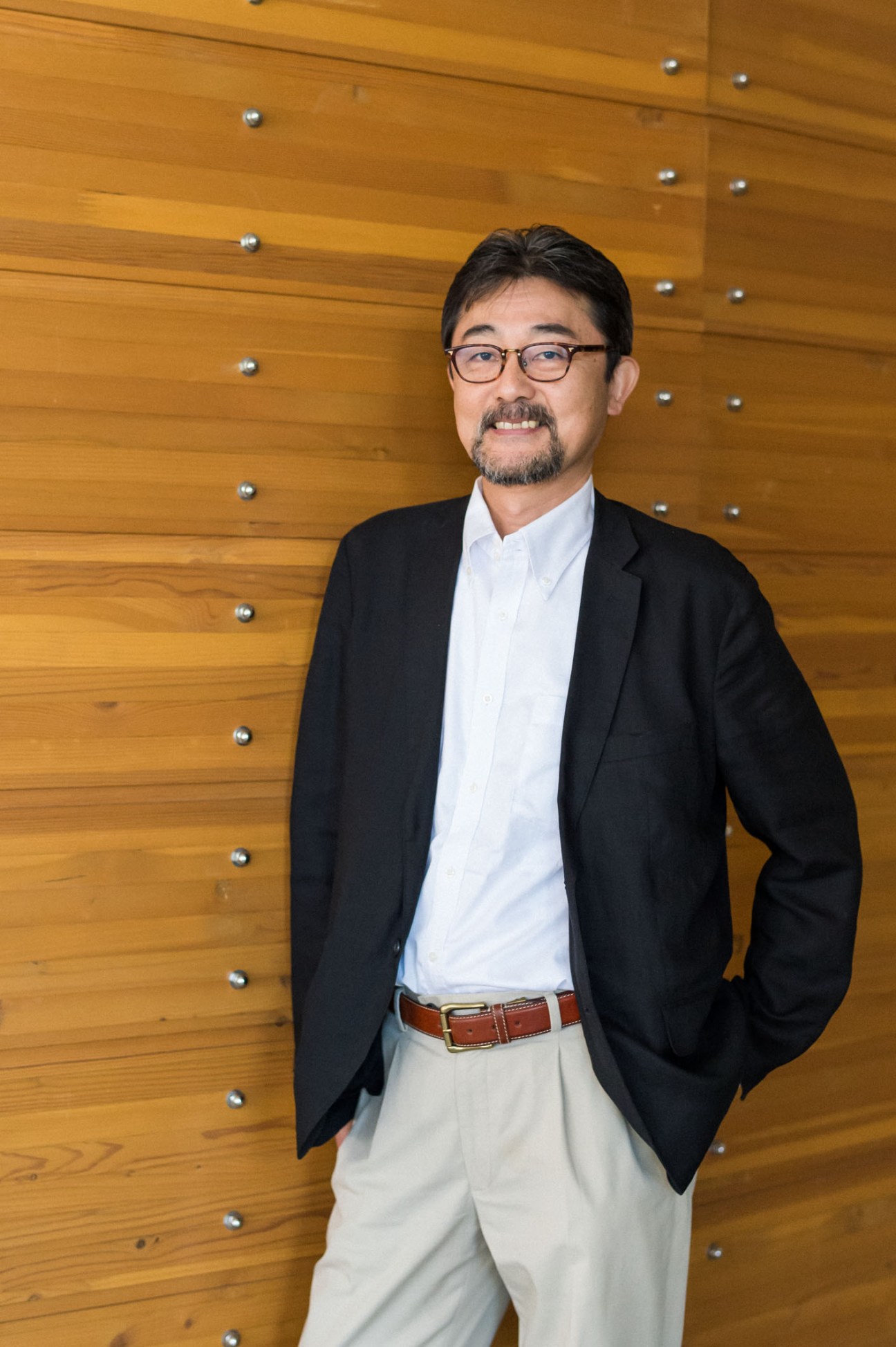 Atsushi Morino, sales director for Hida Sangyo, standing against a wooden wall.