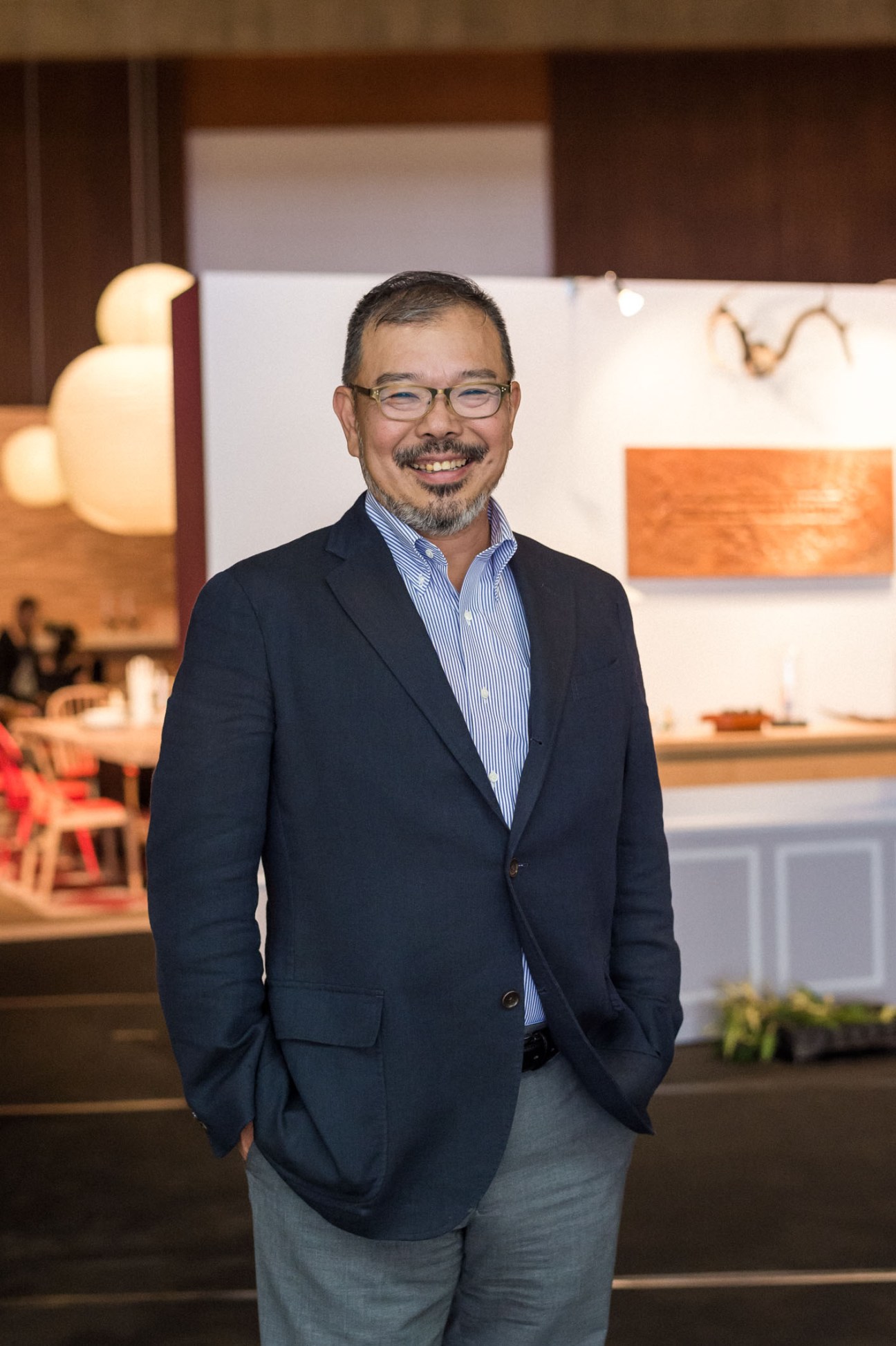 Katsunori Shirakawa, chairman of the Hida Woodworking Federation, smiling in a furniture showroom.