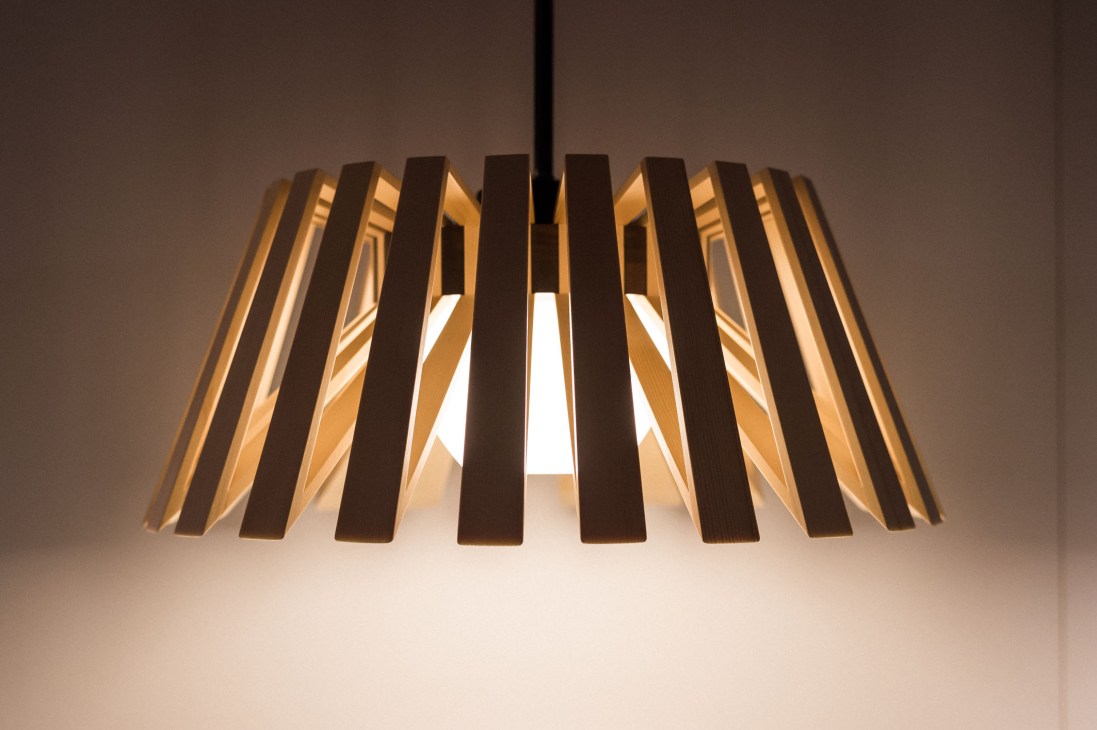 Rita wooden light by Moare, a pendant fixture with vertically-slotted natural and dark wood slats radiating from a central opening
