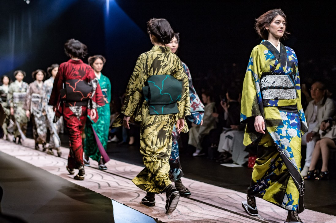 Models wearing traditional kimono with modern designs walk down a runway at Jotaro Saito fashion show.