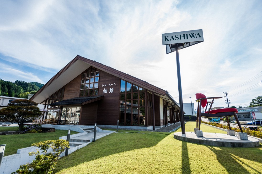 Kashiwa furniture company's modern wooden showroom and workshop building in Takayama with a street sign.