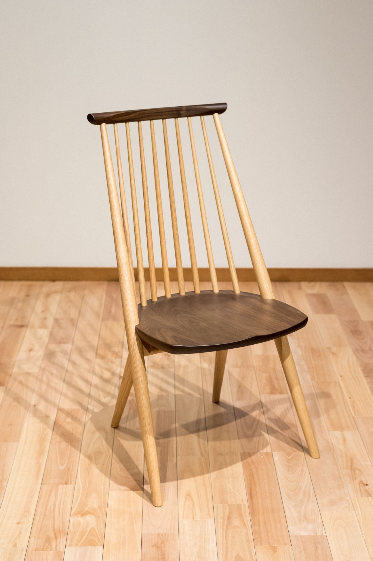 Civil chair designed by Toshihiko Ushimaru for Kashiwa, featuring light wood spindle back and dark seat.