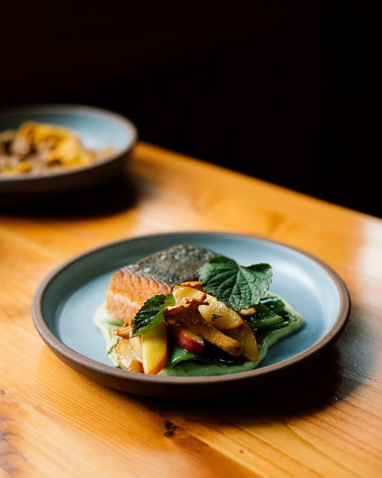 King salmon dish with vegetables and herbs plated on ceramic dinnerware