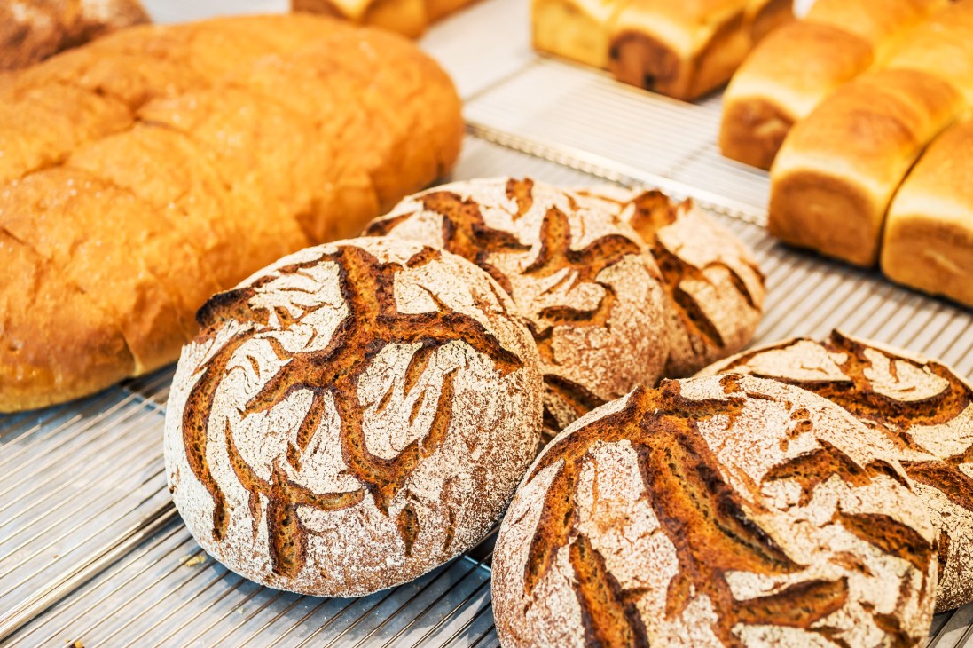 Assorted fresh bread loaves and rolls displayed on a striped cloth at Nior bakery.