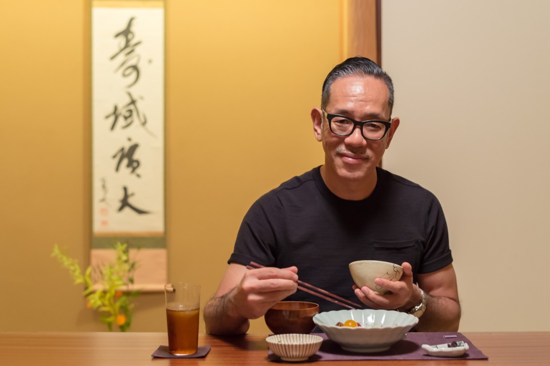 Fashion designer Naoki Takizawa eating with chopsticks at a table in a Japanese restaurant.