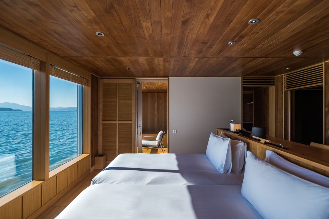 A spacious Guntu guest room with wood-lined walls, large windows overlooking the Seto Inland Sea, and two beds with white linens.