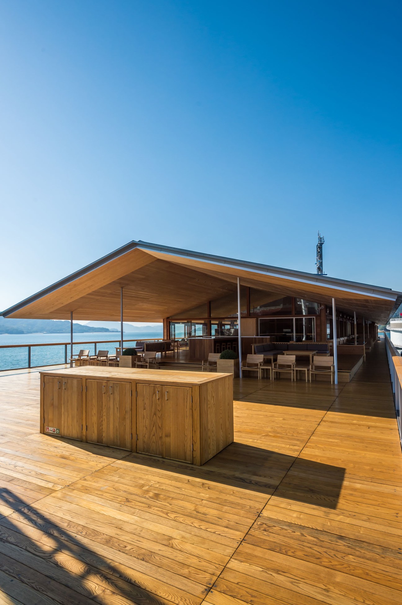 Wooden deck seating area aboard Guntu with ocean views and clear blue sky
