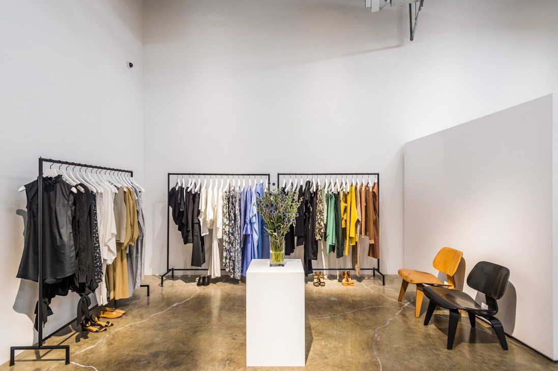 Graphpaper fashion shop interior with white walls, clothing racks, and vintage chairs.