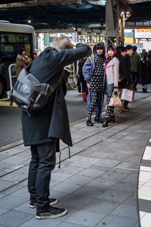 Street style photographer capturing two fashionably dressed young women outside Hikarie venue during Tokyo Fashion Week.