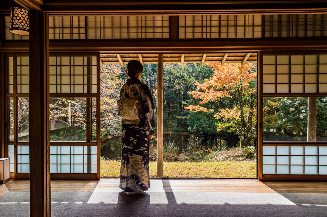 Akiko Matsuoka in traditional kimono standing in the historic Hyosekikaku building with forest views through large shoji screens.