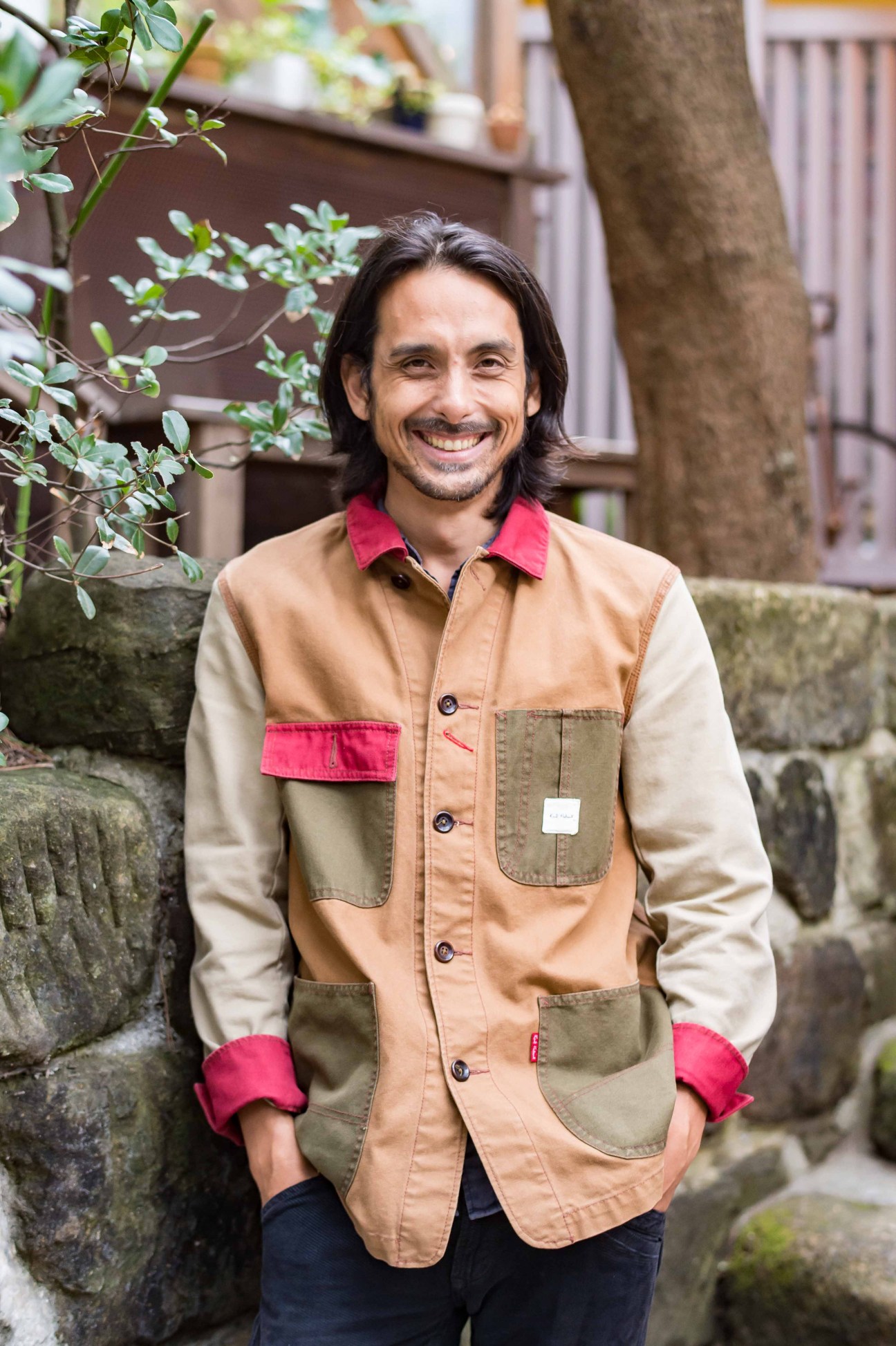Gen Nagashima, co-founder of Cinema Amigo, wearing a patchwork jacket and smiling in an outdoor setting