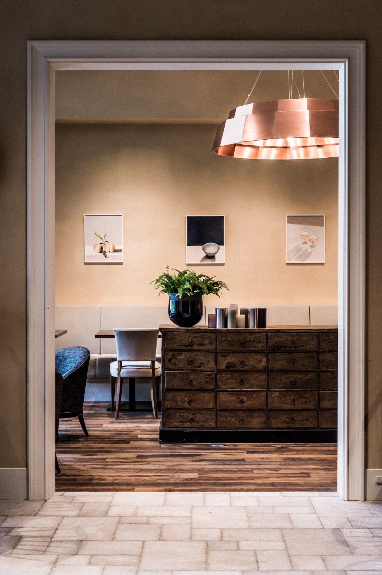 Interior view of Trunk Hotel's restaurant Trunk Kitchen with wooden furniture, copper pendant light and framed artwork.