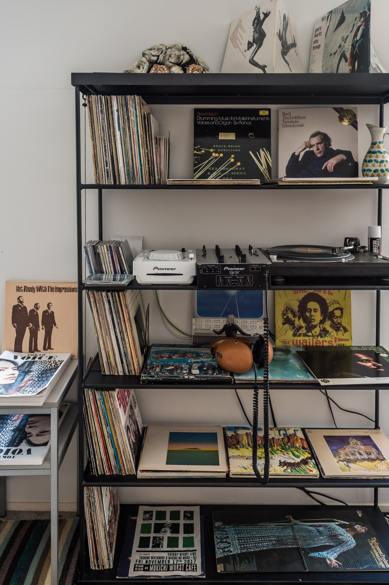Vinyl records collection displayed on black shelving unit with turntables and audio equipment
