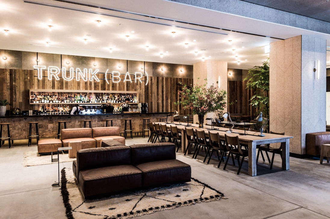 Trunk Hotel's all-day lounge and bar with neon signage, wooden walls, leather seating, and bar counter.