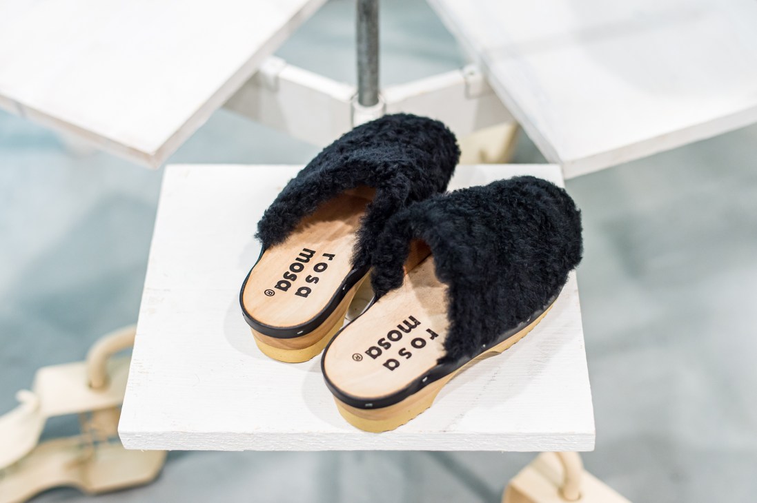 Black shearling clogs with wooden soles and Rosa Mosa branding on white surface