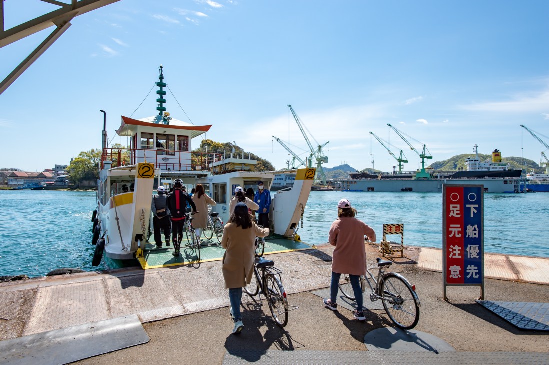 Ferry terminal at Onomichi waterfront with cyclists and passengers boarding a ferry boat.