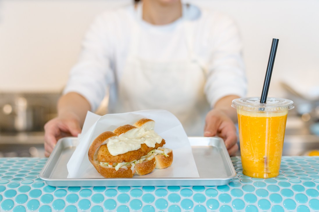 Fried-fish sandwich and orange juice served at Onomaru Shouten's kiosk in Onomichi Station.