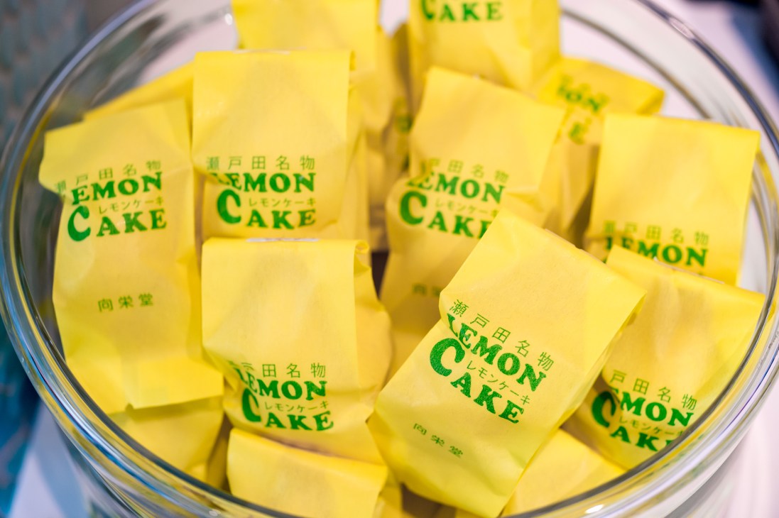 Packaged lemon cakes with yellow wrappers and green text displayed in a clear container.