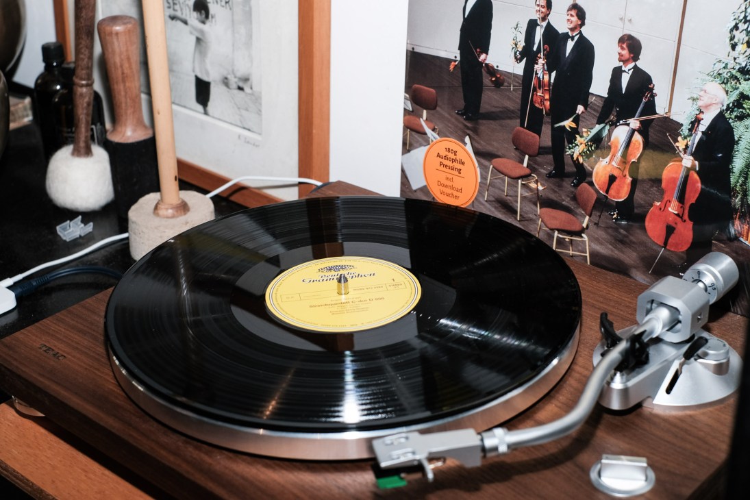 Vintage record player with yellow label vinyl record on wooden surface surrounded by audio equipment