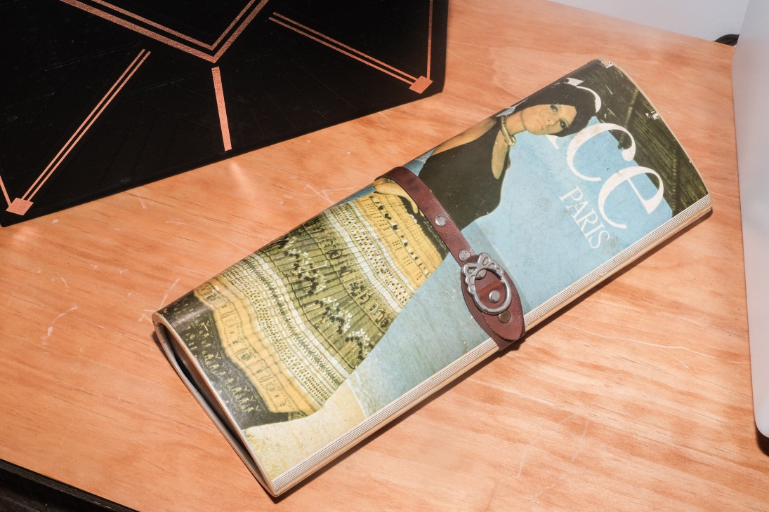 An open book or magazine with a leather clutch bag placed on its pages.